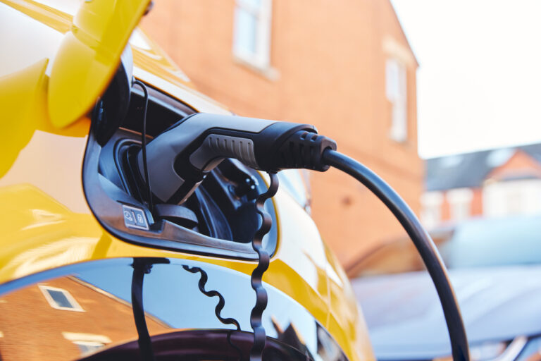 Electric car charging outside house on street