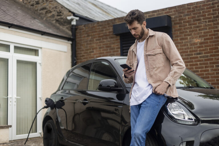 Man checking phone by black electric vehicle