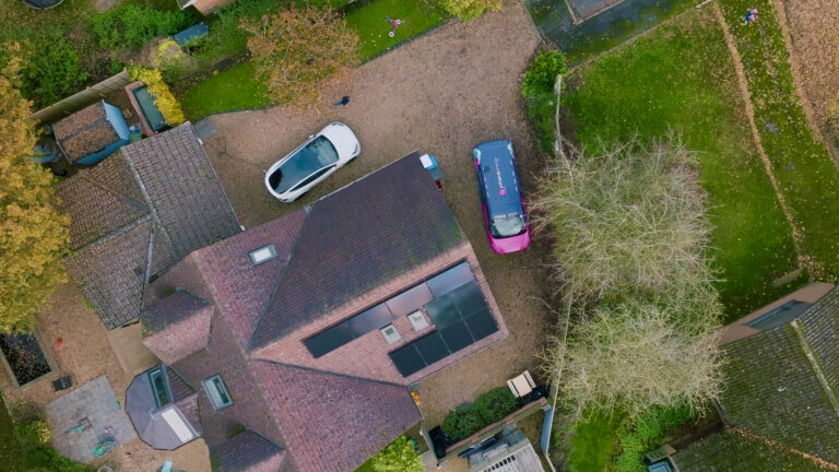 Aerial view of a residential property with solar install and EV car.