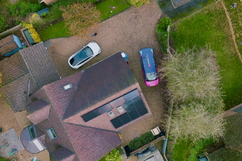 Aerial view of a residential property with solar install and EV car.