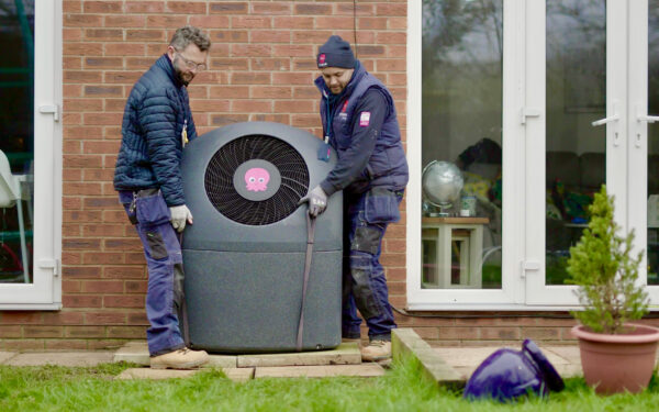 Two men installing an air source heat pump