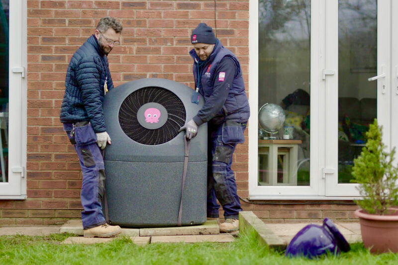 Two men installing an air source heat pump