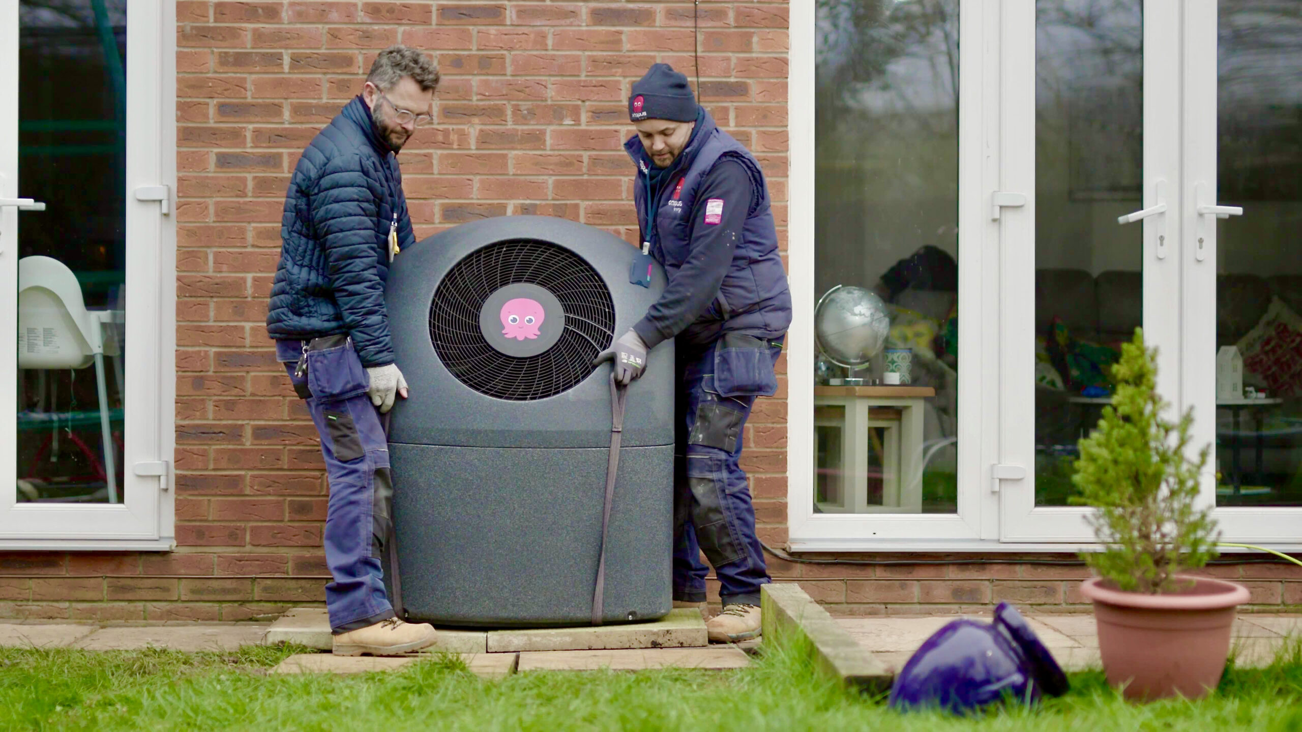 Two men installing an air source heat pump