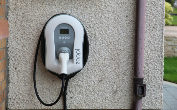 Myenergi Zappi vehicle charger with cable and plug on the wall outside a house in UK