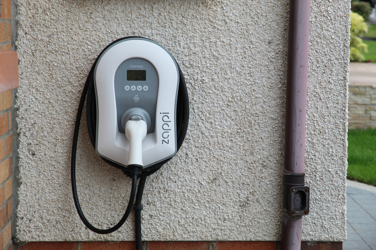 Myenergi Zappi vehicle charger with cable and plug on the wall outside a house in UK