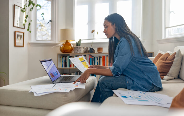 Woman working on laptop with documents