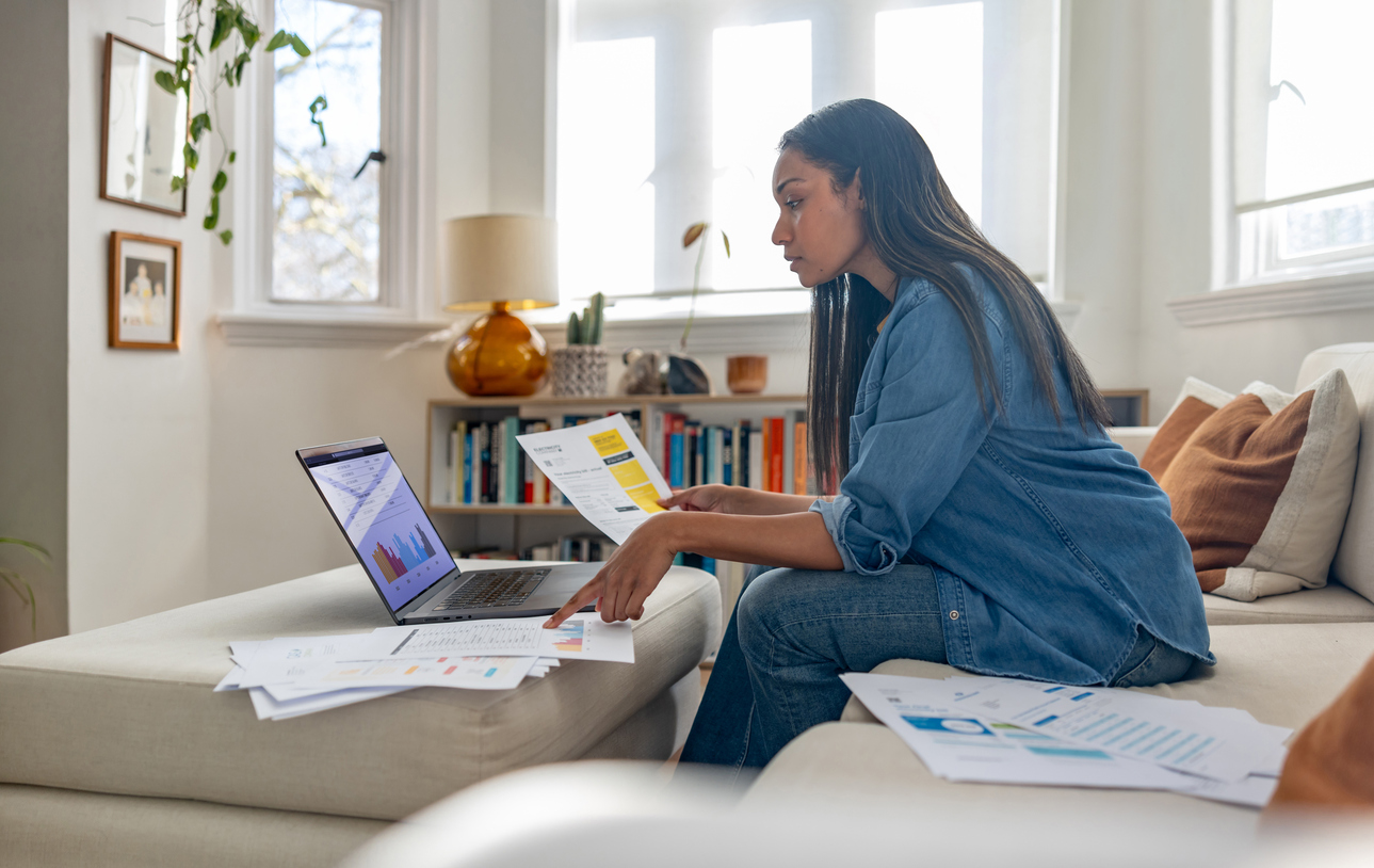 Woman working on laptop with documents